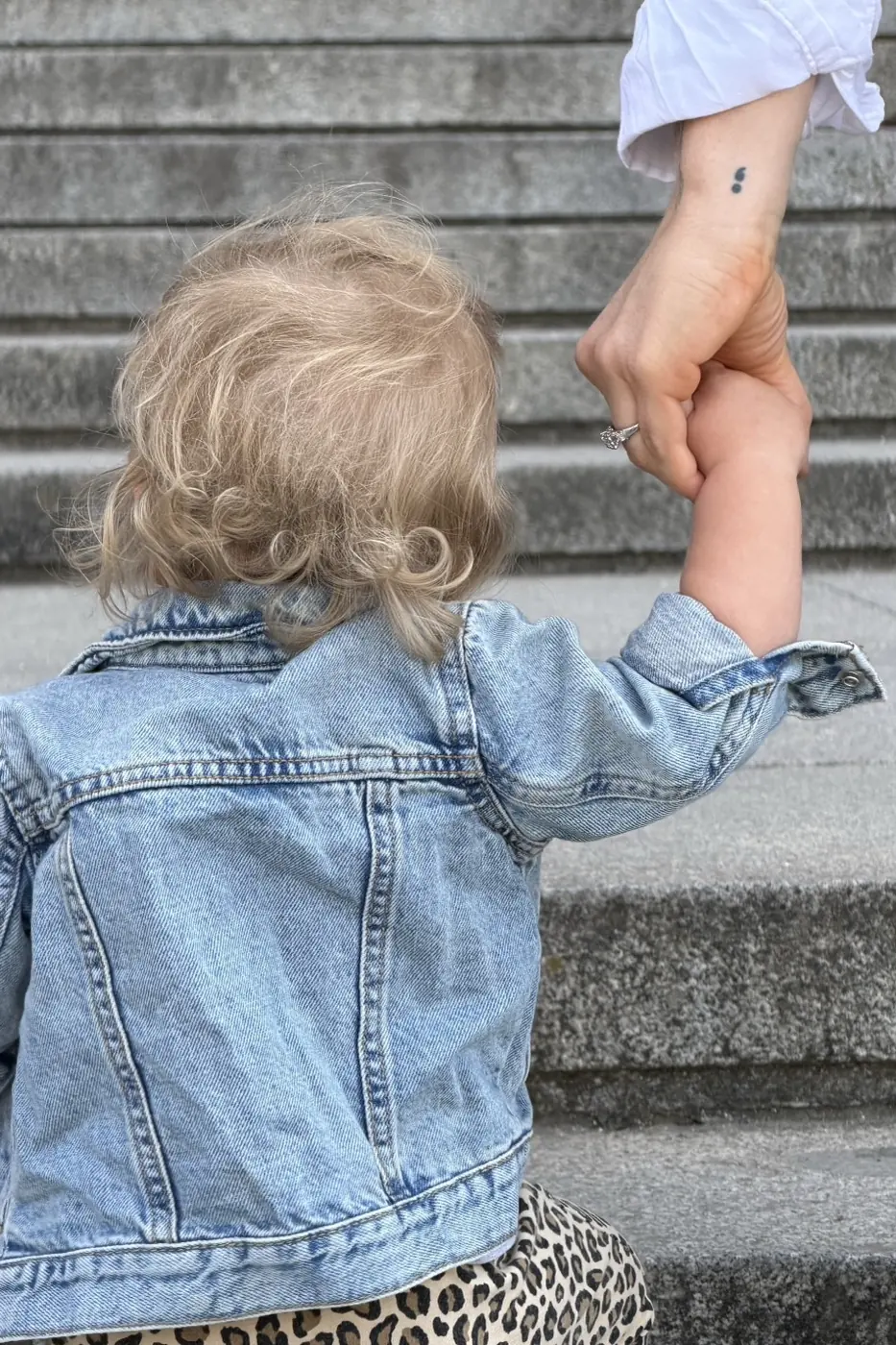 Madeleine holding her young daughter's hand on a walk outdoors